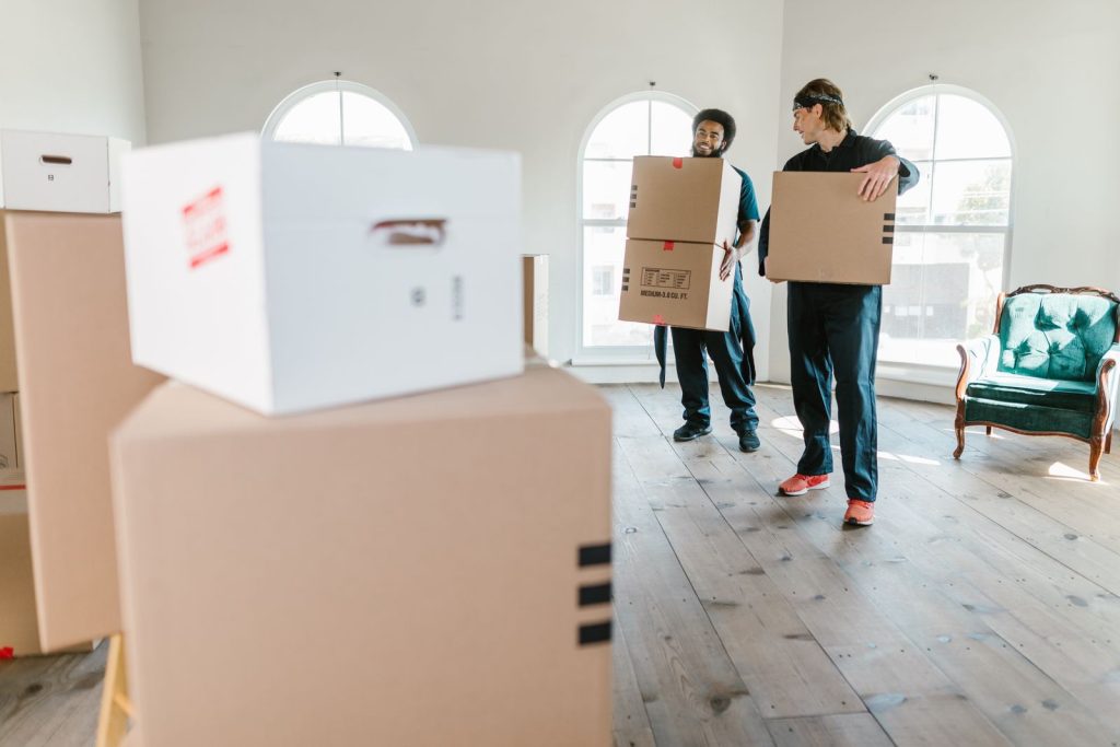 Moving boxes labeled by room and stacked ready to load